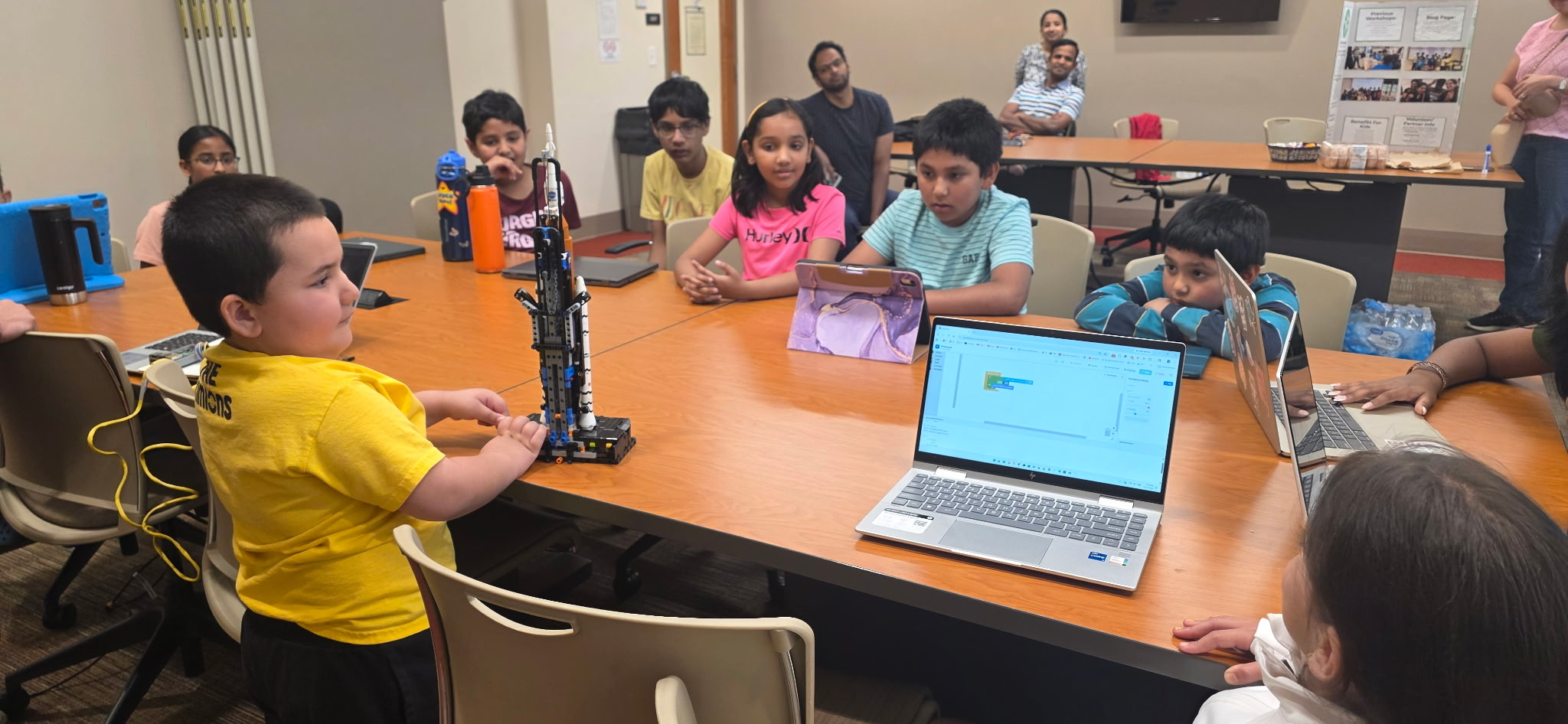 A student presenting a LEGO rocket model to fellow STEM Sprouts students
